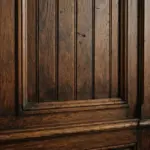 Dark wooden wainscoting with vertical panels serves as the foreground in a dimly lit room with blurred booth seating